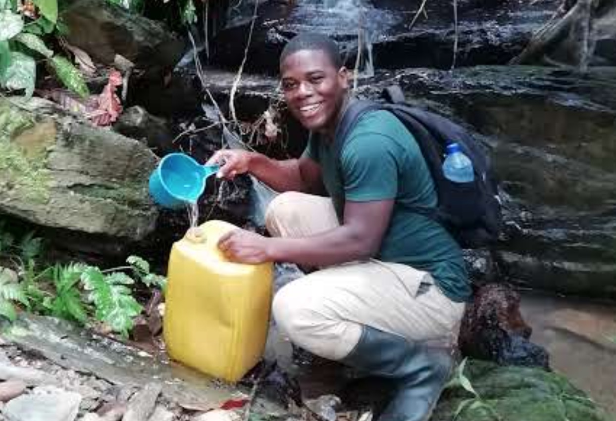 Eric fetching water from a stream during work on cocoa farm, Southwestern Ghana